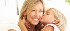 Daughter Giving Mother Kiss Relaxing On Sofa